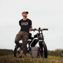 Man sitting on a motorcycle in a field wearing a 'Texas Nature' t-shirt.